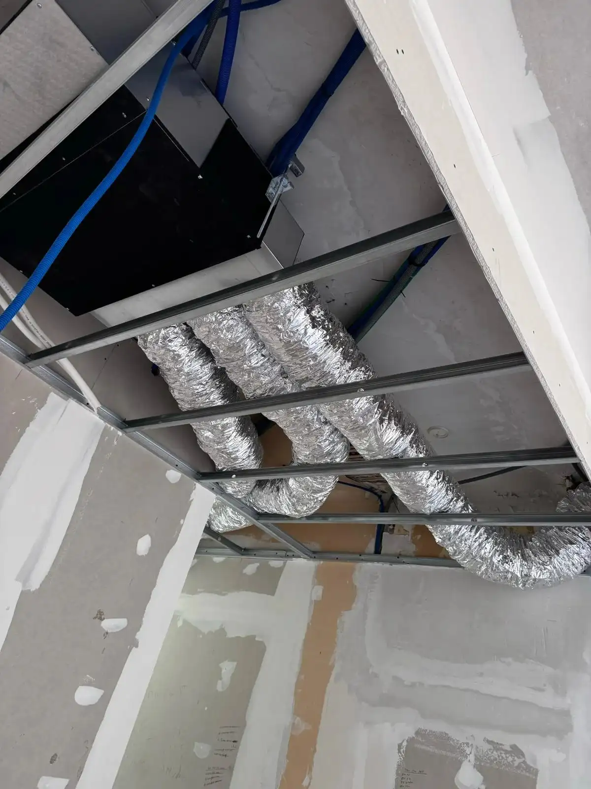 Une équipe de techniciens installant et vérifiant une unité de climatisation intérieure.