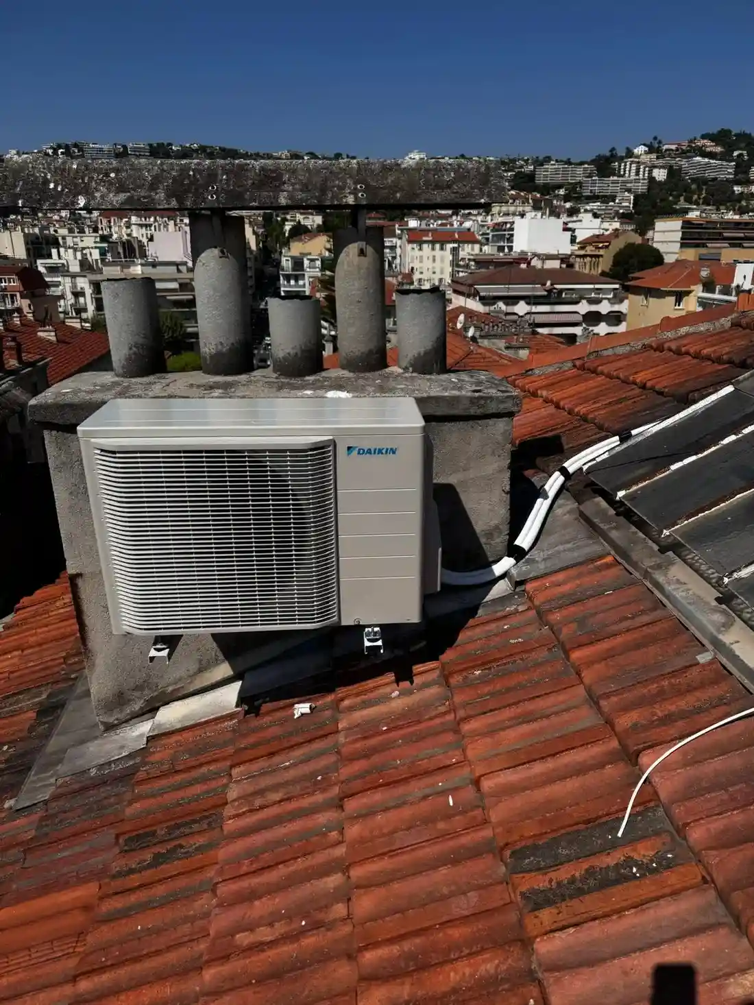Unité de climatisation intérieure soigneusement dissimulée dans un meuble avec des portes à lattes en bois.