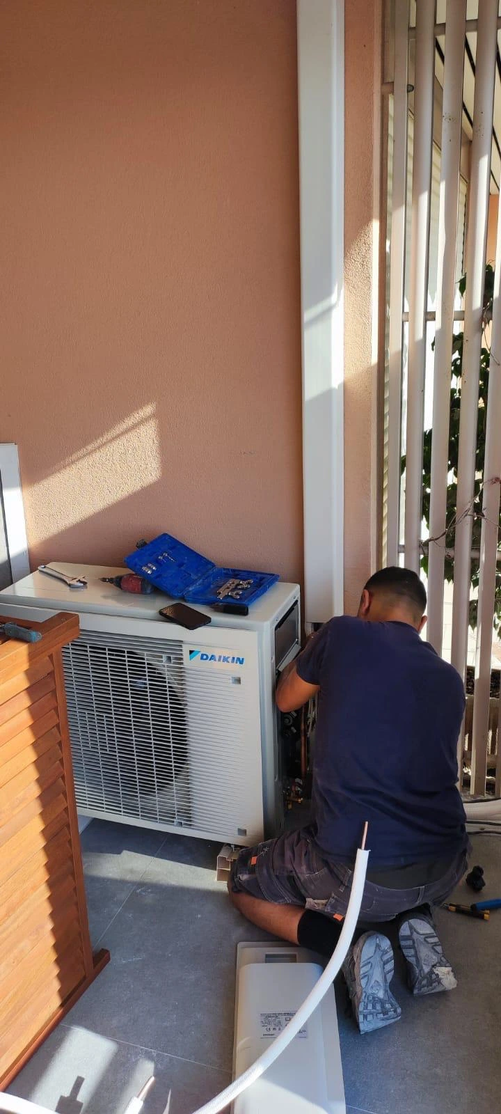 Technicien installant une unité de climatisation Daikin.